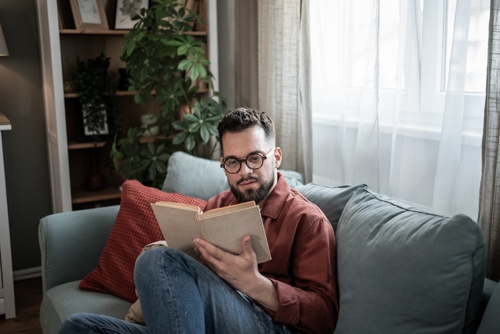 Man sitting on a sofa reading a book in residential rehab